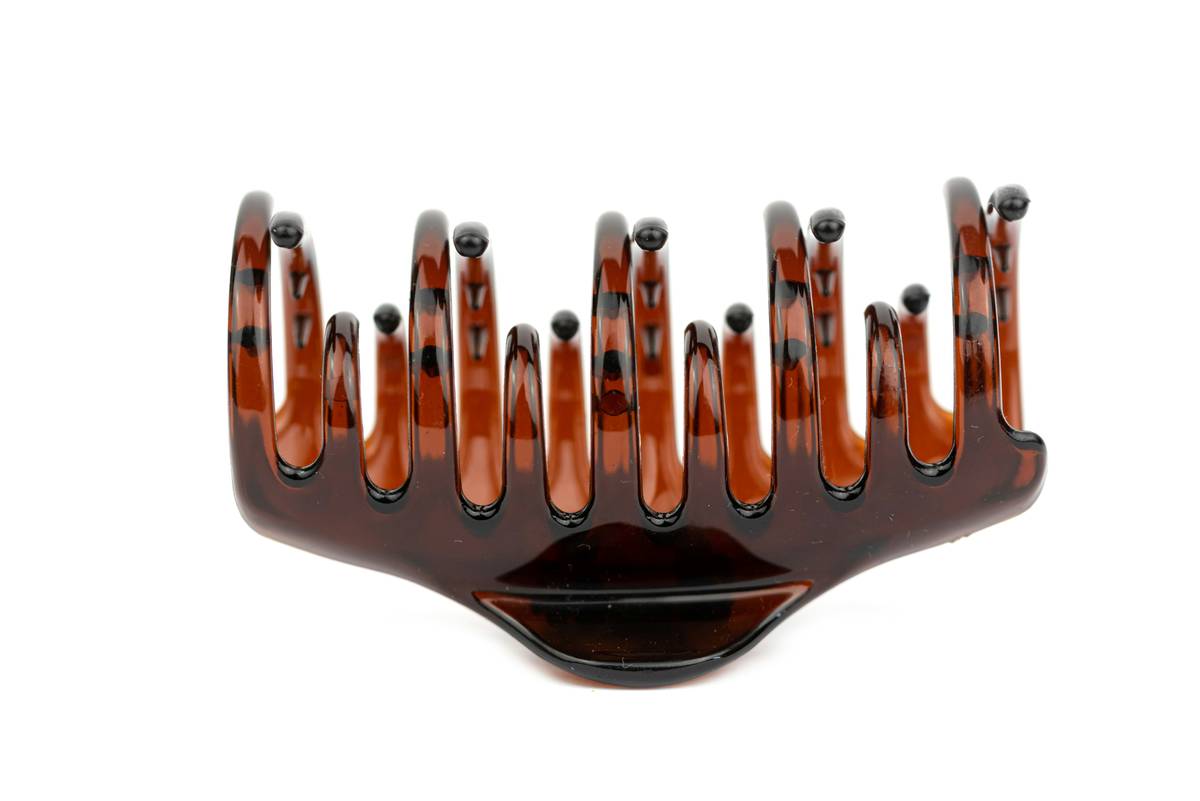 Close-up of using a brow shaping comb to lift eyebrow hairs upward for natural arch definition